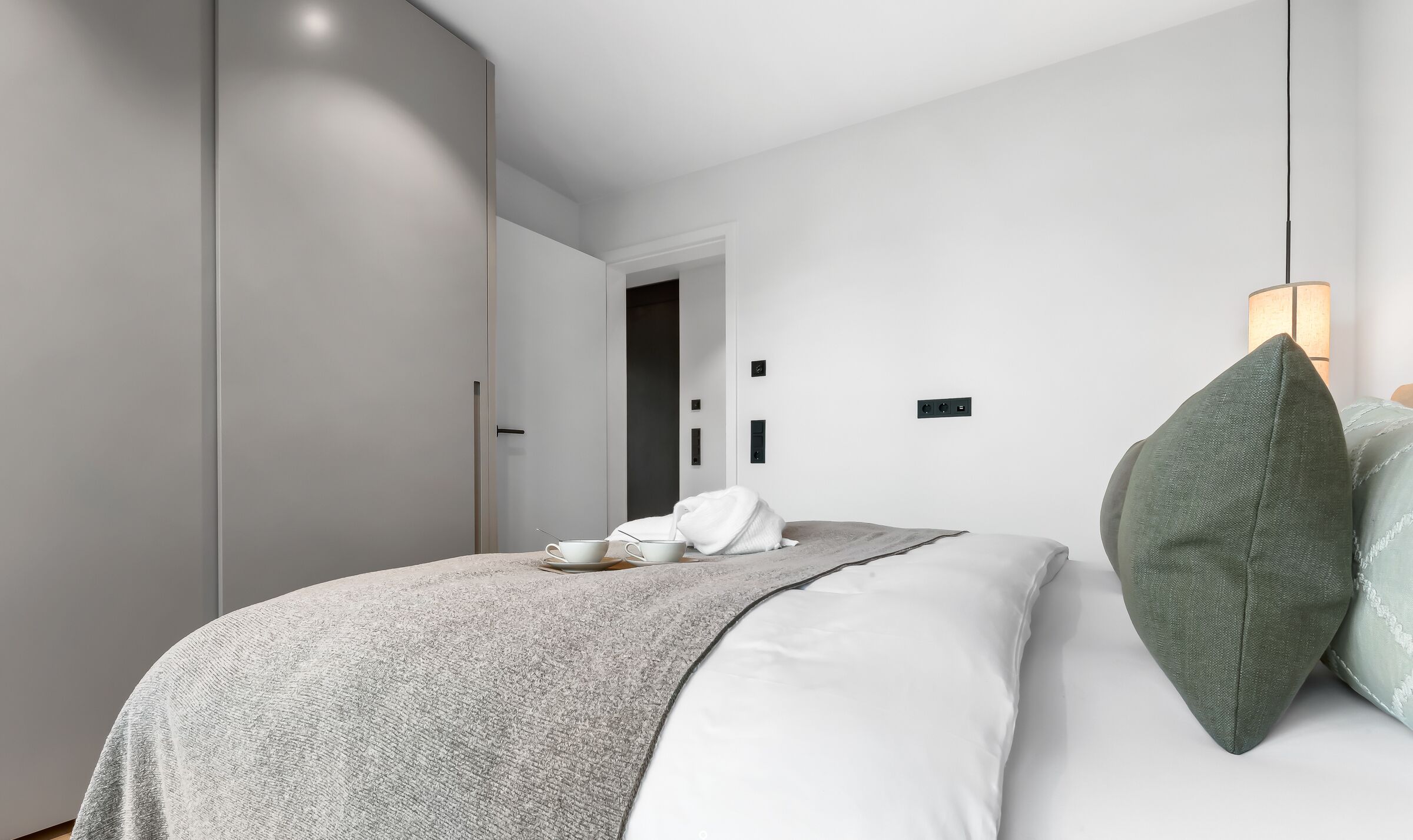 A modern bedroom with a bed, bedside table, and a wardrobe.