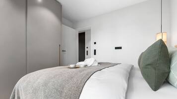 A modern bedroom with a bed, bedside table, and a wardrobe.