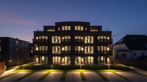 A multi-story building with balconies and large windows, surrounded by a well-maintained lawn and pathway. - Manhattan Suit – New Luxury Spread Across 2 Floors with Finnish & Infrared Sauna (List auf Sylt)