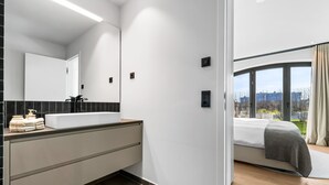 A modern bathroom with a large mirror, white sink, and black tiles. - Manhattan Suit – New Luxury Spread Across 2 Floors with Finnish & Infrared Sauna (List auf Sylt)