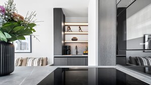 A modern kitchen with a built-in coffee maker, a sink, and a decorative shelf with figurines.