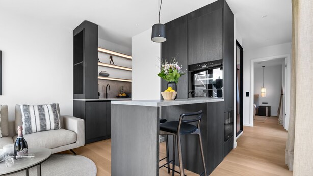A modern kitchen with a central island, dark cabinetry, and a pendant light.