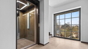 A modern elevator with a sleek design and a large window on the right side.