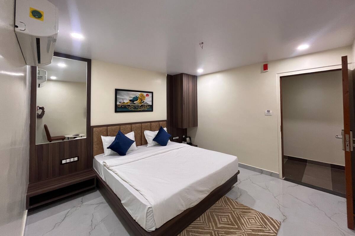 A hotel room with a bed, a mirror, a painting on the wall, and a wardrobe.