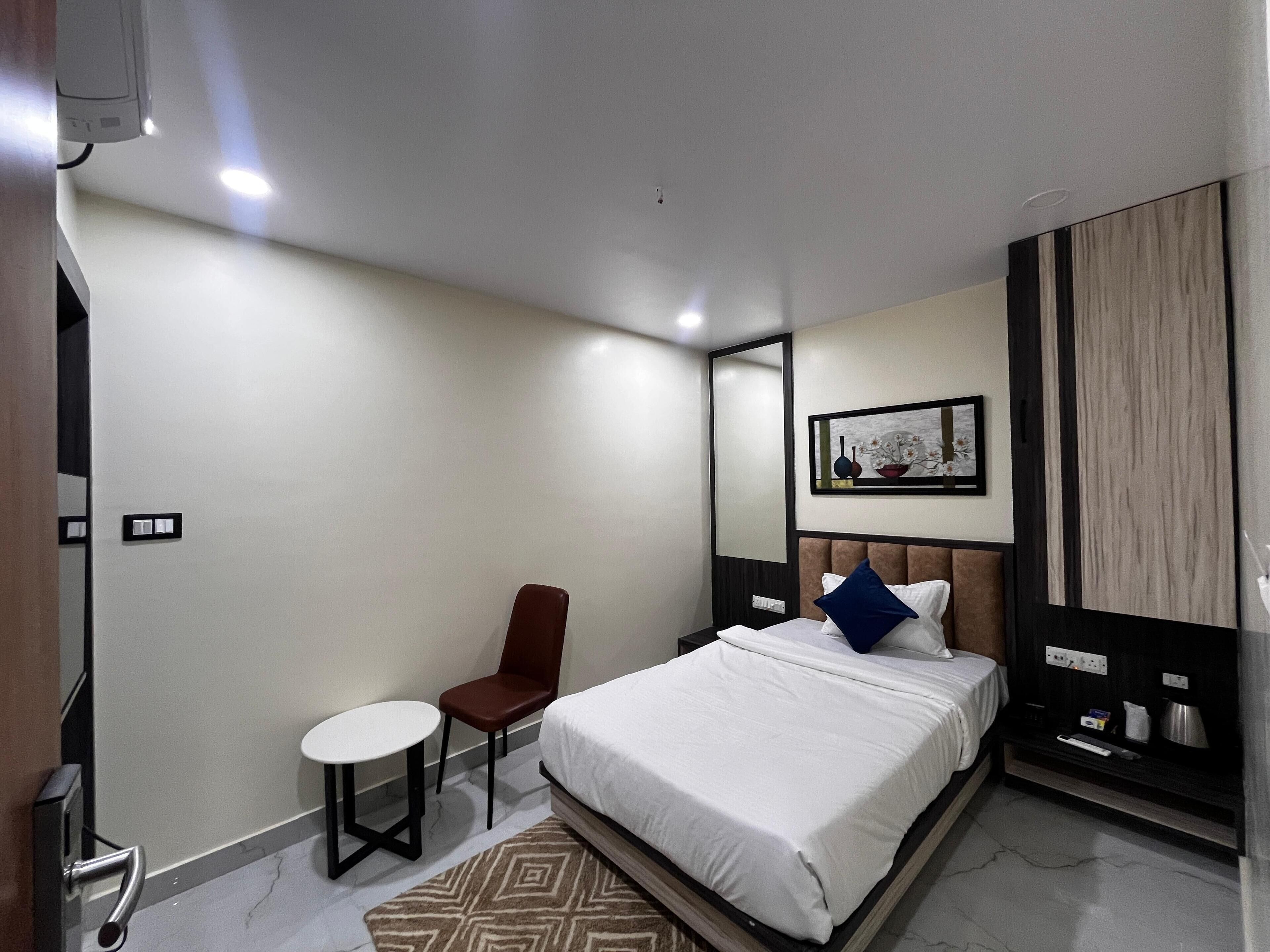 Una camera d'albergo moderna con un letto, un tavolino, una sedia e un comodino.