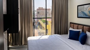 Ein Hotelzimmer mit einem großen Bett, einem Fernseher und einem Fenster mit Vorhängen.