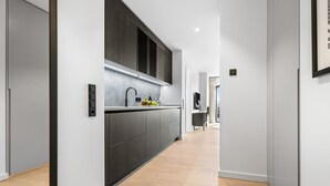 Une cuisine moderne avec des meubles de couleur sombre, un évier en acier inoxydable et un four encastré.