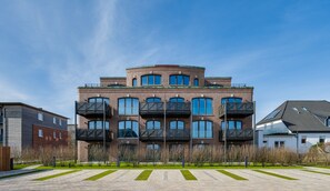 Un edificio residencial de varios pisos con balcones, fachada de ladrillo y techo plano.