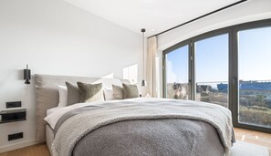 Un dormitorio moderno con una cama grande, vistas a la ciudad y un balcón.