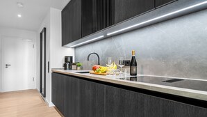 Une cuisine moderne avec des meubles de couleur sombre, un plan de travail en acier inoxydable et une cave à vin intégrée.