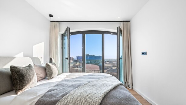 Une chambre moderne avec un grand lit, une vue sur un port et un puits de lumière.