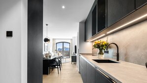 Une cuisine moderne avec un plan de travail en marbre, un évier et un vase rempli de fleurs.