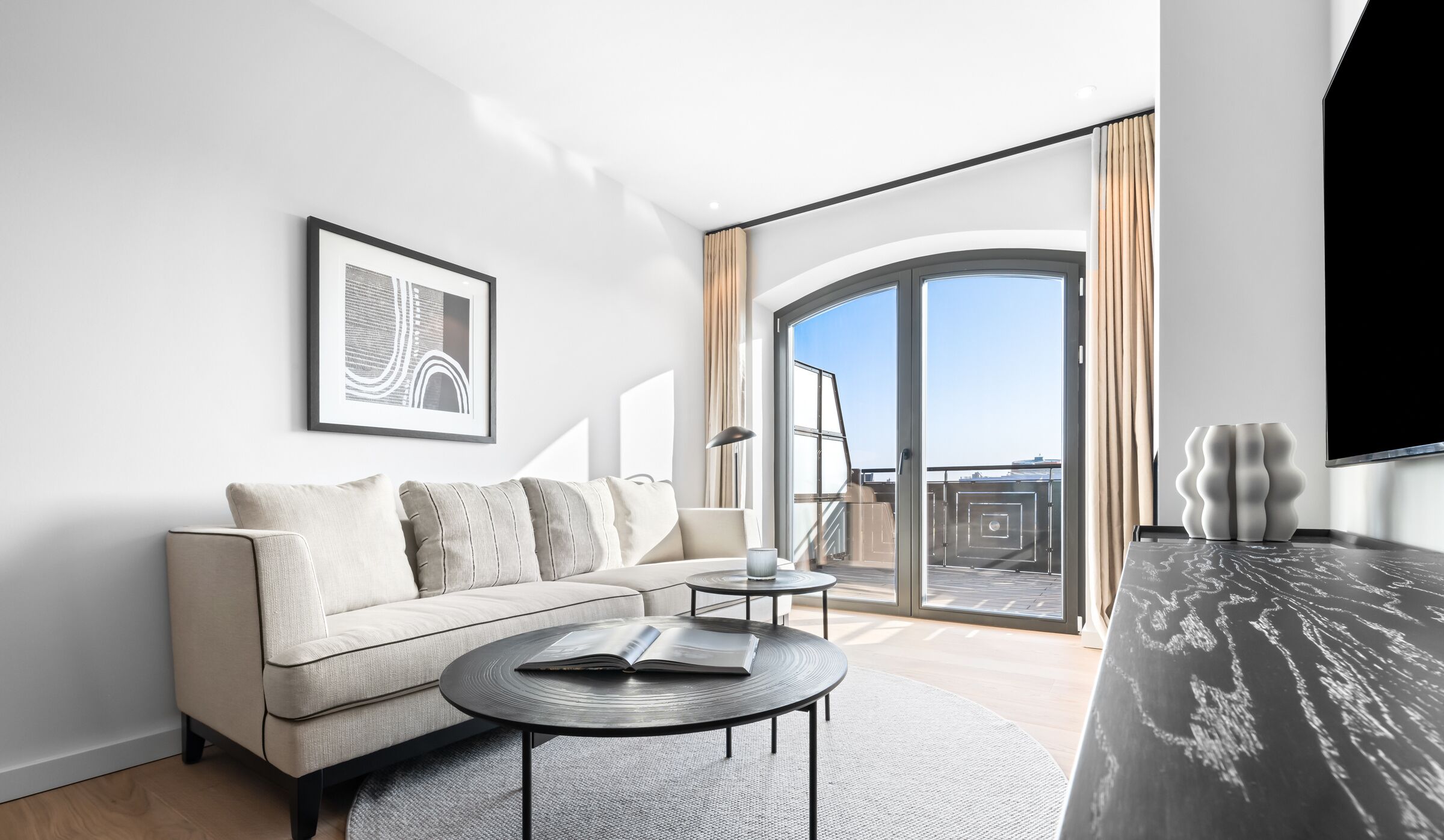 Una sala de estar moderna con un sofá, una mesa de centro y un ventanal con vistas a la ciudad.