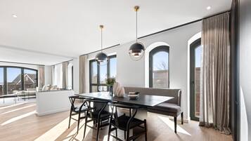 A modern kitchen with a dining area, large windows, and a view of the outside.