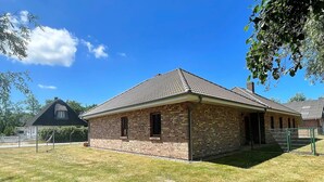 A single-story brick building with a tiled roof, a small porch, and a fenced yard. - Your Perfect Getaway: Cozy Holiday Home in the Tranquil Countryside! (Rodenäs)