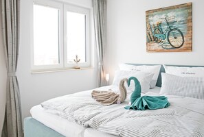Un lit bien fait, avec une literie à rayures, une serviette turquoise et un coussin en forme de cygne.