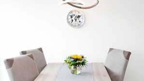 A dining table with four chairs, a vase with flowers, and a world map clock on the wall. - Modern penthouse (55 sqm) open all year round for 2 to 4 people in the Staffel (Norderney)