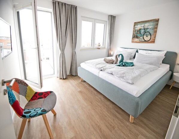 Une chambre à coucher avec un lit, une chaise, une fenêtre et un tableau accroché au mur.