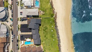 Vista aerea di una zona residenziale costiera con case, una piscina e una spiaggia.