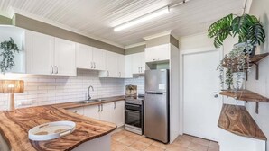 A modern kitchen with white cabinets, a stainless steel refrigerator, and a wooden countertop. - Absolute Beachfront Apartment 8B - 1 bedroom (Lennox Head)