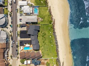 Vista aérea de una zona residencial costera con casas, una piscina y una playa.
