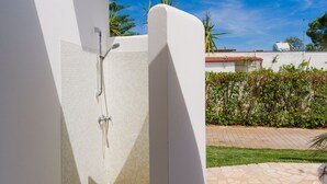 Un espace douche moderne avec un mur carrelé, une douchette à main et un robinet mural.