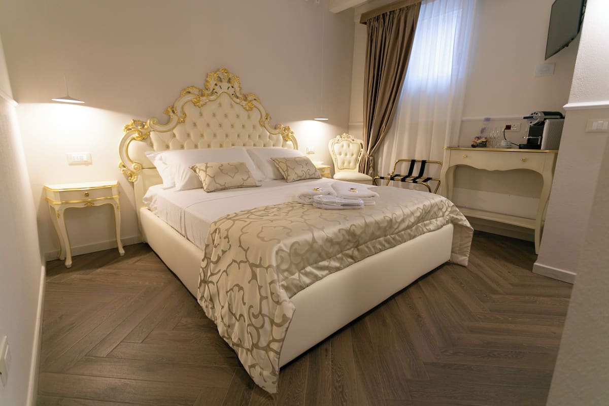 A bedroom with a large bed, a nightstand, a chair, and a desk.