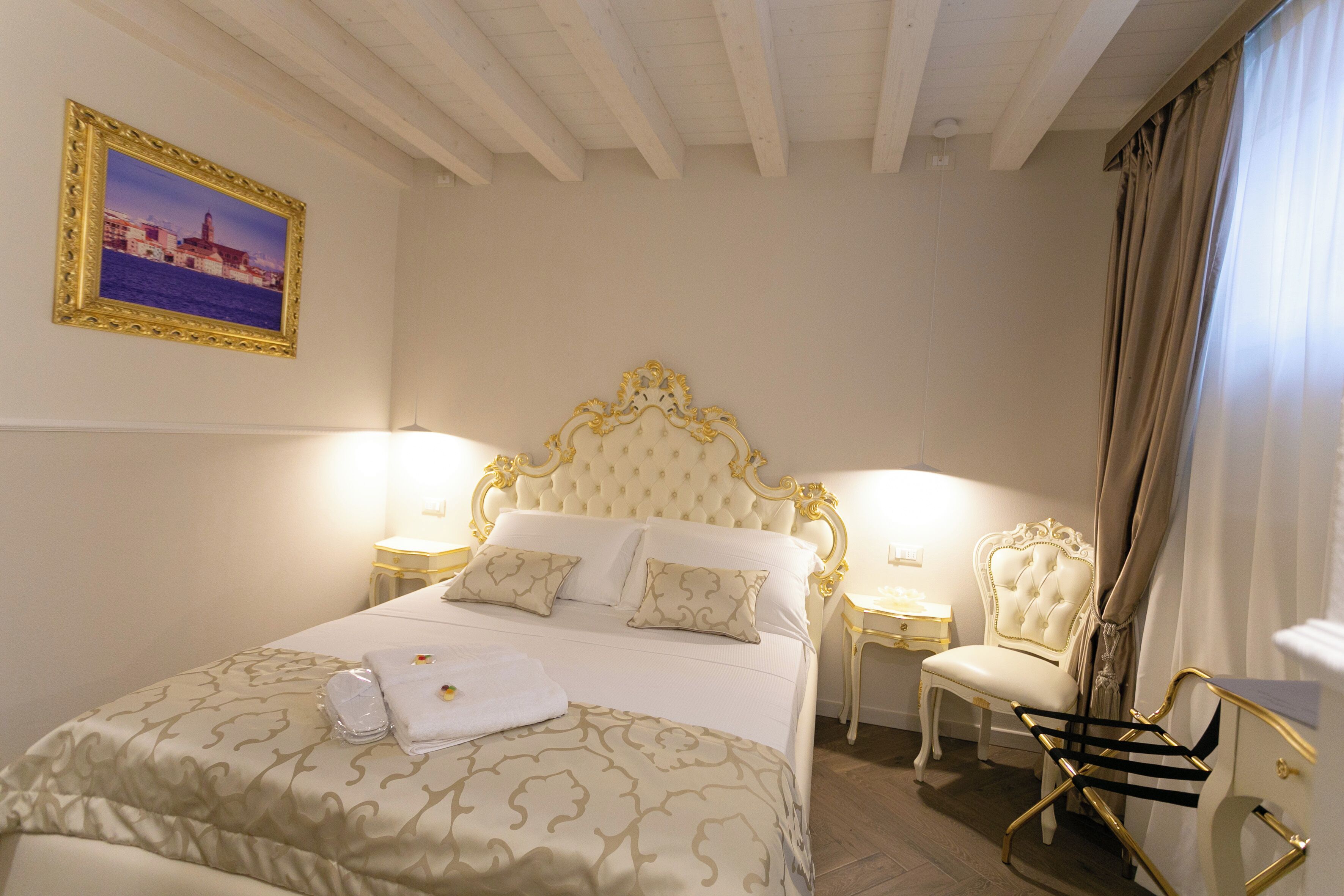 A hotel room with a large bed, two bedside tables, a chair, and a picture on the wall.