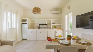 Une cuisine moderne avec des meubles blancs, un four encastré et un coin repas avec une table dressée pour deux personnes.