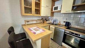 A compact kitchen with wooden cabinets, a microwave, a dishwasher, and an oven. - Apartment Fruk 5 (Jadranovo)