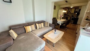 A living room with a sofa, a coffee table, and a kitchen in the background. - Apartment Fruk 5 (Jadranovo)