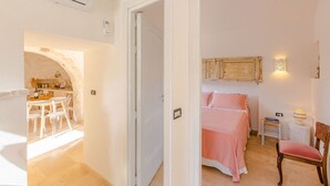 Quarto com cama, mesa de cabeceira, cadeira e luminária na parede.