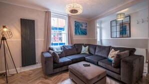 A modern living room with a sectional sofa, a floor lamp, and artwork on the walls. - Green Retreat (Dartmouth)