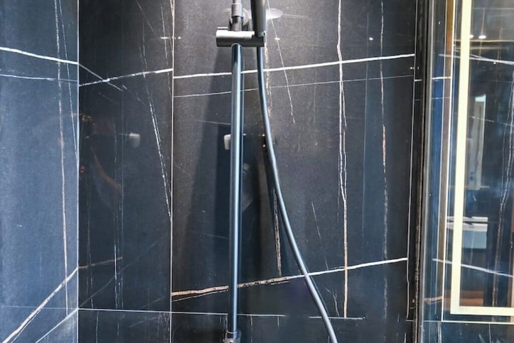 A bathroom with black marble walls and a visible plumbing fixture.