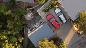 Eine Vogelperspektive auf ein Wohngebiet mit mehreren Häusern, einer gepflasterten Einfahrt und einem roten Auto, das vor einem Haus parkt.