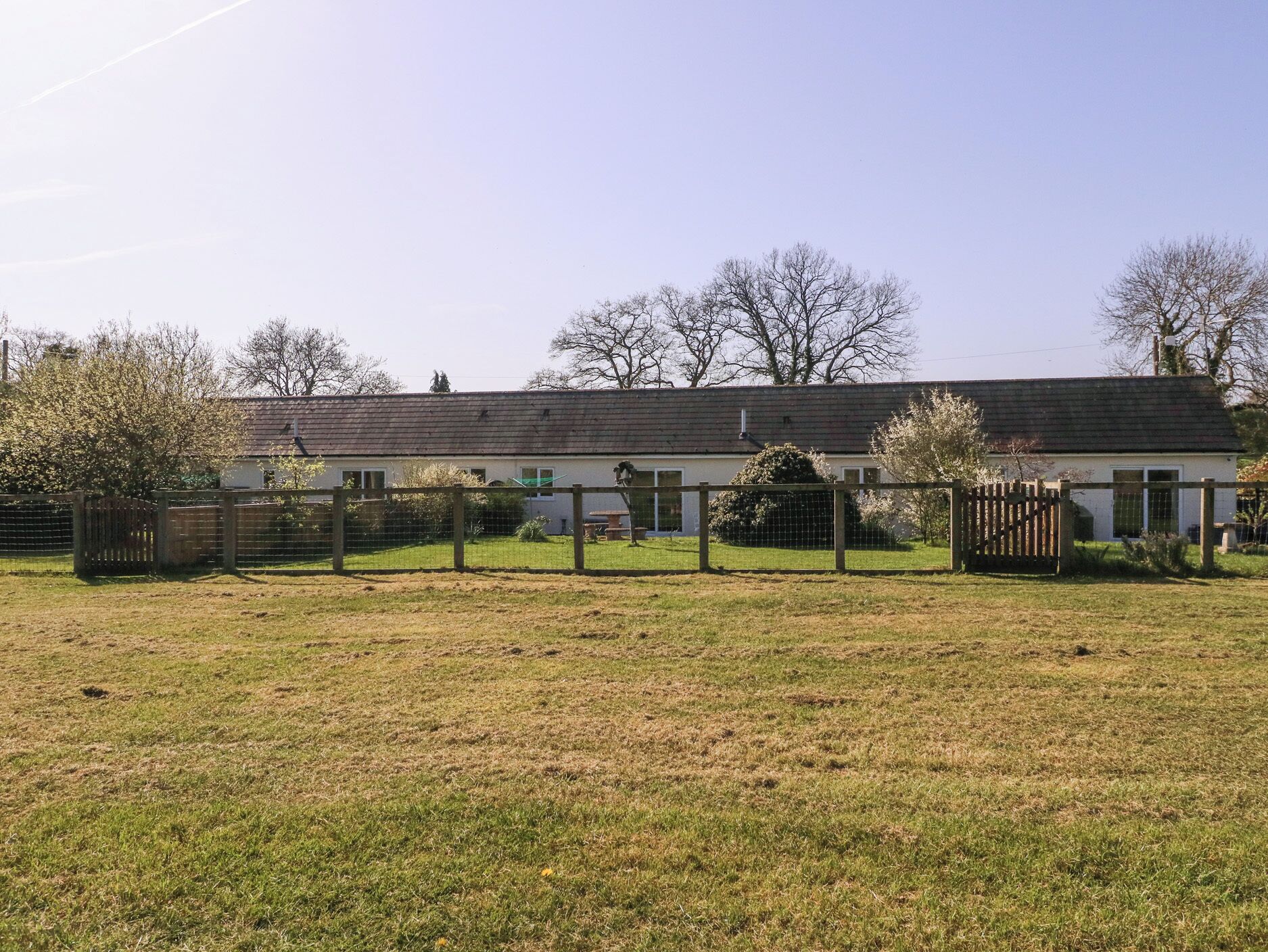 A single-story building with a flat roof, surrounded by a fenced yard.