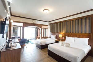 Una habitación de hotel con dos camas, un escritorio con una silla, un televisor y un ventanal grande.