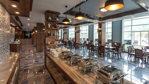 A spacious restaurant with a long buffet line, wooden decor, and large windows offering a view of the outdoors. - Le Erawan Hotel (Phang Nga)