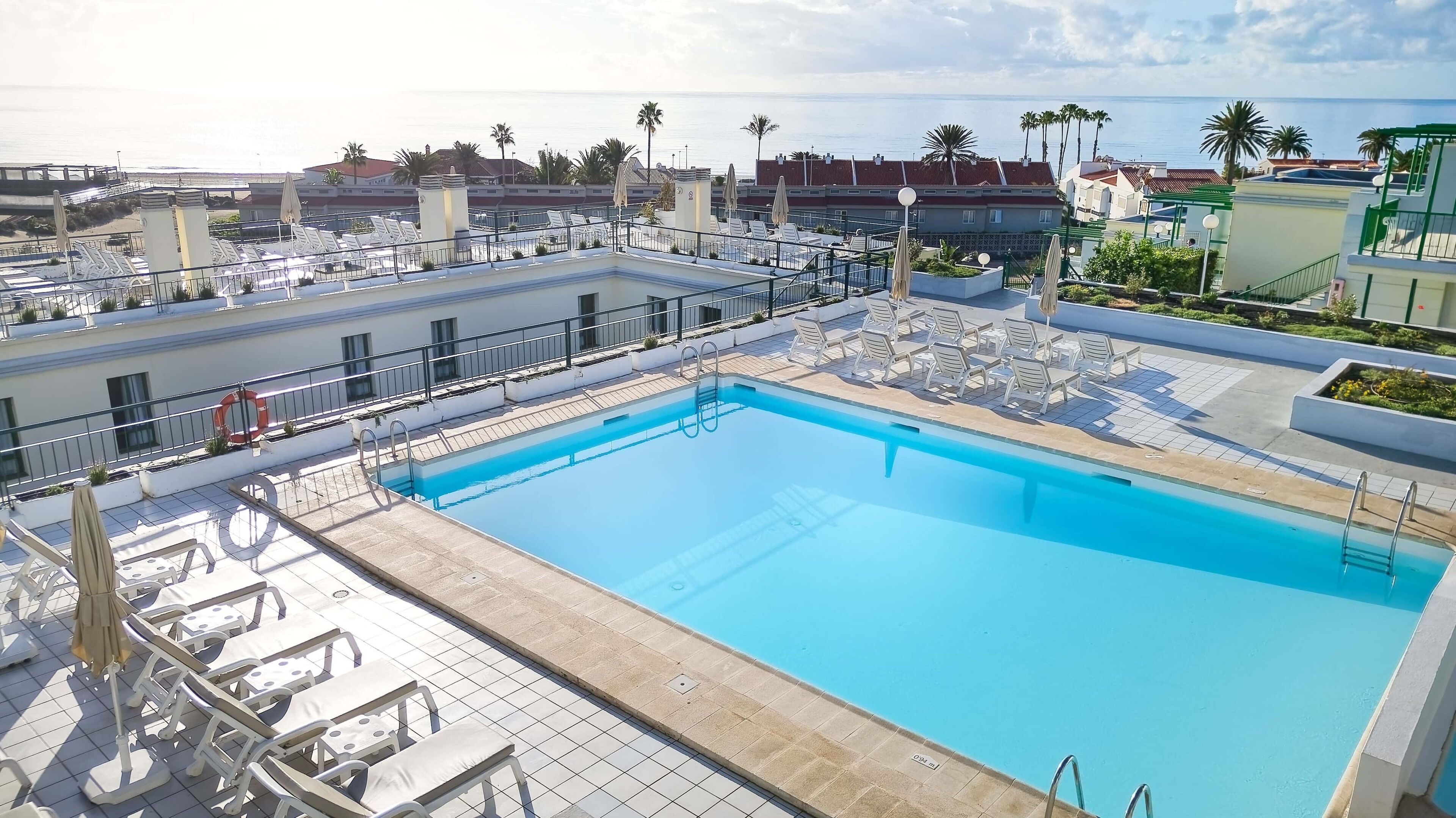 A rooftop pool with lounge chairs and a view of the sea.