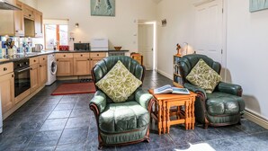 A spacious living room with green leather armchairs and a wooden coffee table. - Yr Hen Ysgubor (Carmarthen)