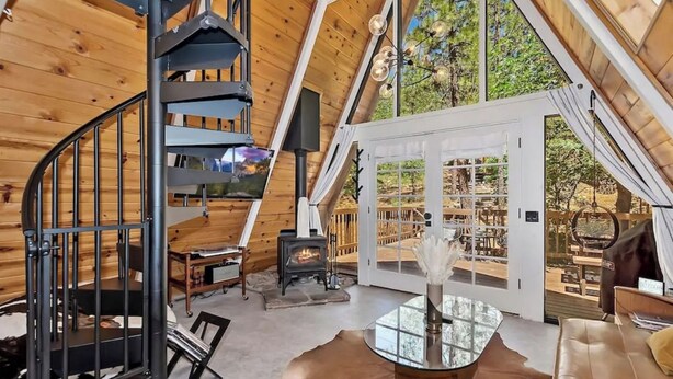 A spacious loft with a spiral staircase, a fireplace, and a large glass door leading to an outdoor deck. - Acute A-frame Cabin w WiFi (Sugarloaf)