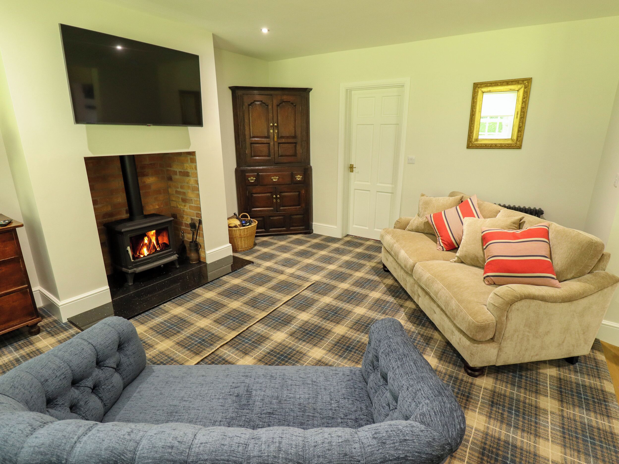A living room with a fireplace, a sofa, a television, and a plaid carpet.