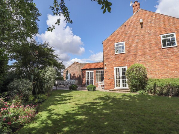 A brick house with a well-maintained lawn and garden.
