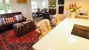 A living room with a sofa, a dining area with a table and chairs, a fireplace, and a kitchen area with a countertop and a vase of flowers. - Moon Field Lodge (Scunthorpe)