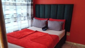 A bed with a red blanket, grey pillows, and a dark headboard. - Neo & ruks guest house goodwood (Cape Town)