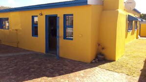 A yellow building with blue-framed windows and a satellite dish. - Neo & ruks guest house goodwood (Cape Town)