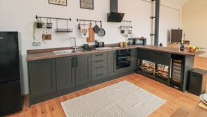 A modern kitchen with dark cabinets, a wooden countertop, a built-in oven, and a hanging pot rack. - The Old Workshop (Scarborough)
