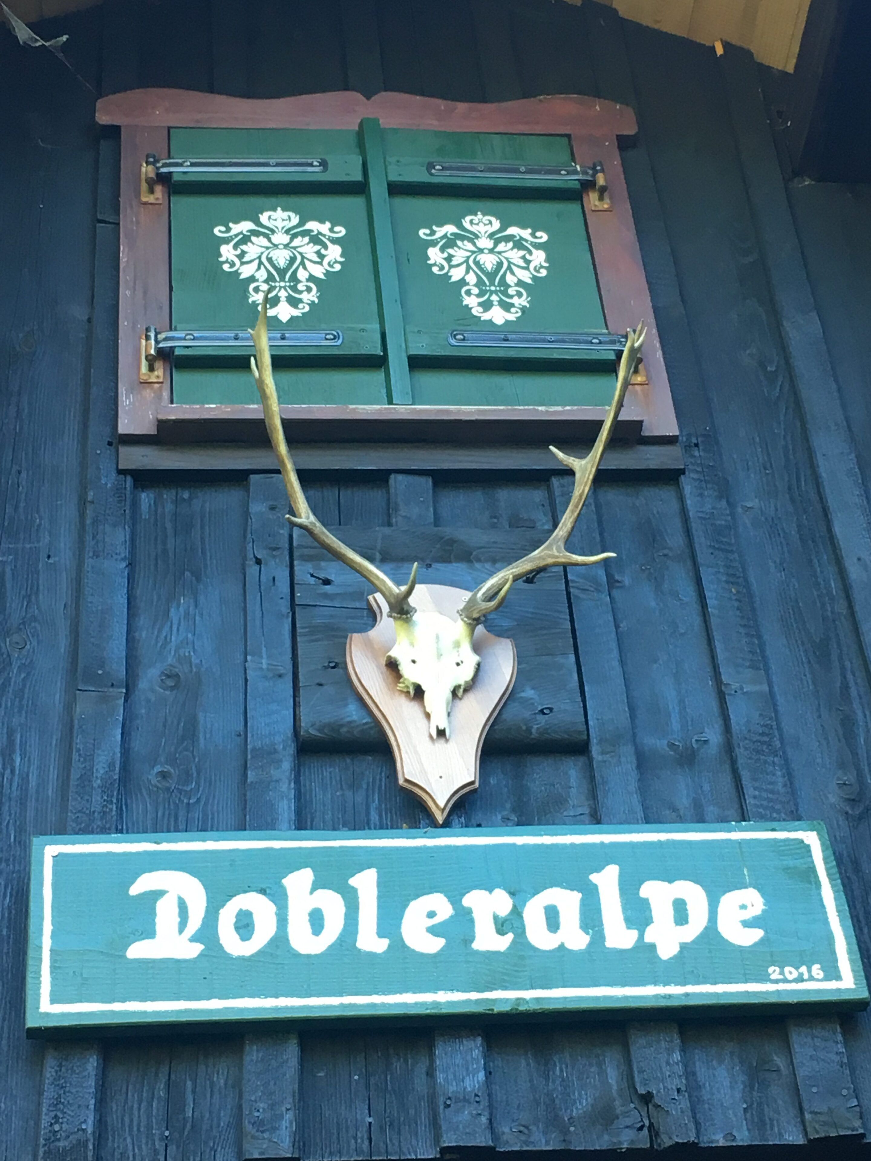 Un letrero de madera con una calavera de ciervo y astas, y el nombre "Dobleralpe".