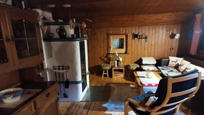 A rustic cabin interior with wooden walls, a kitchen area with a refrigerator, wooden cabinets, and a dining area with a table and chairs. - Tobleralpe cozy self-catering hut in the Allgäu / Oberreute near Oberstaufen (Oberreute)