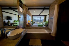 A modern bathroom with a large sink, bathtub, and a view of a green outdoor area. - The Plains Green Ambawela (Nuwara Eliya)